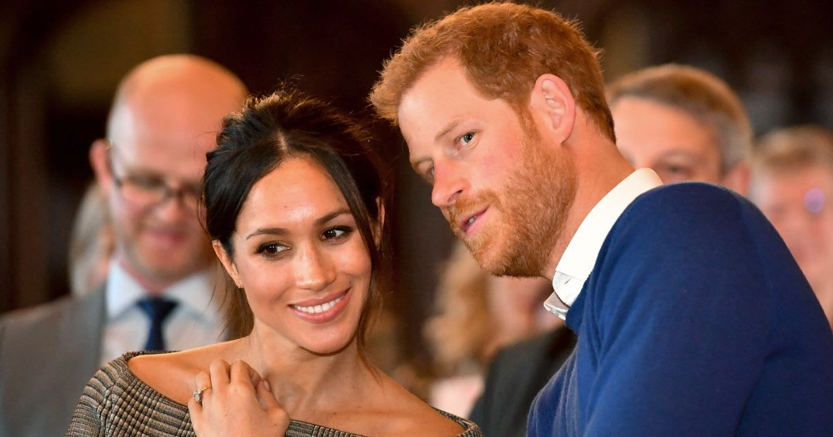 Prince Harry whispers to Meghan Markle as they watch a dance performance by Jukebox Collective in the banqueting hall during a visit to Cardiff Castle. (Cover Image Source: Getty Images | Ben Birchall - WPA Pool)