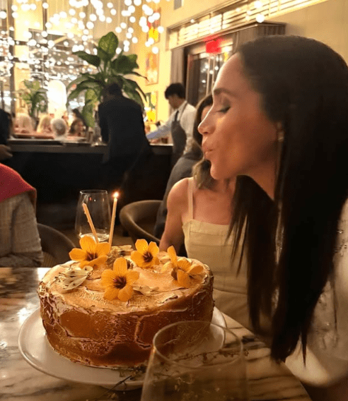 Meghan Markle blowing the candle on her birthday cake in 2025