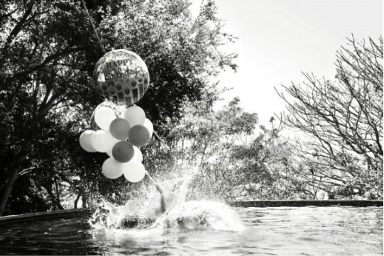 Meghan Markle jumping in the swimming pool holding birthday balloons on her 45th birthday