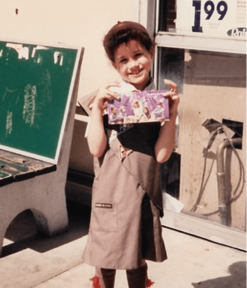 Meghan Markle holding a box of cookies as a Girl Scout during her childhood days